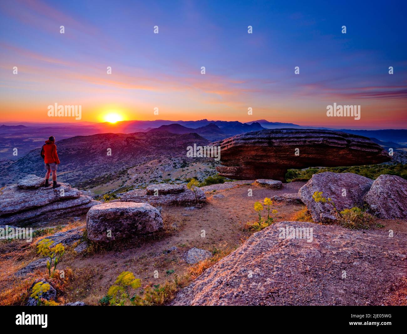 Randonneur debout au lever du soleil, près de la formation rocheuse calcaire de Sombrerillo, réserve naturelle El Torcal, Torcal de Antequera, province de Malaga, Andalousie Banque D'Images