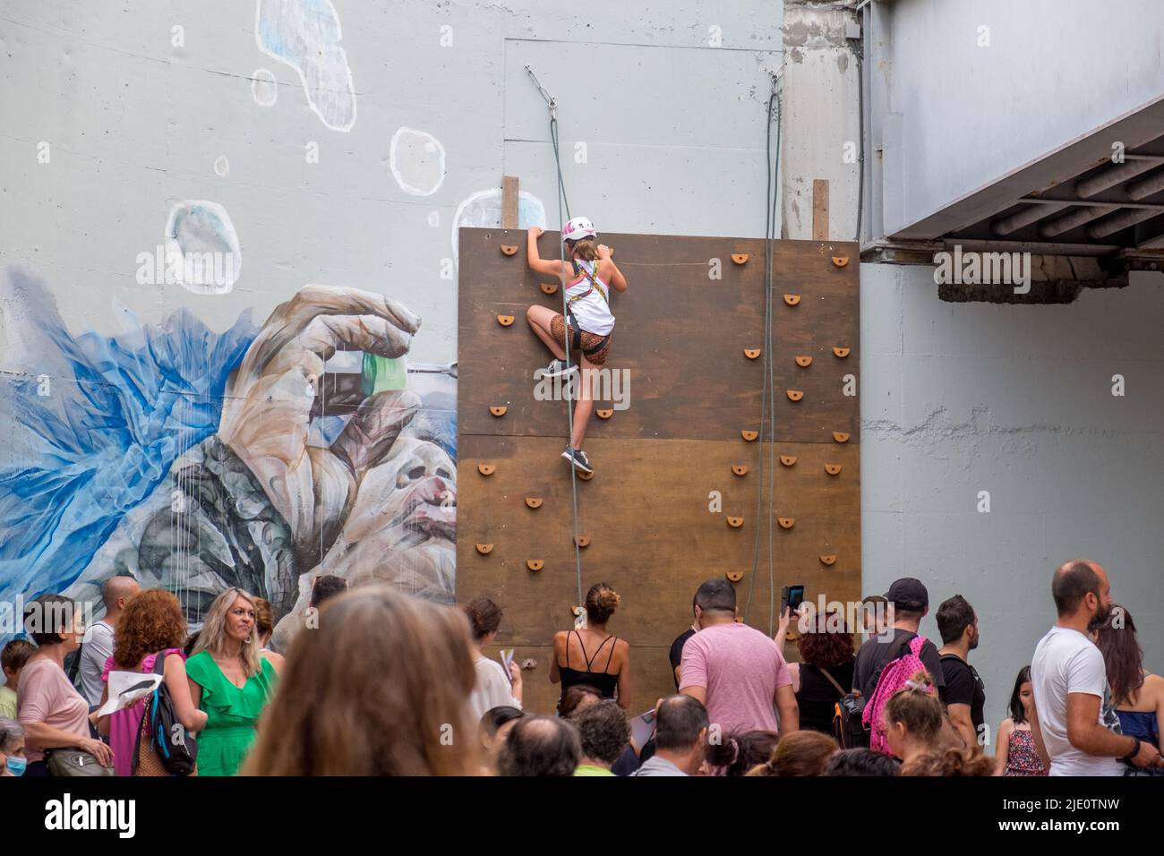 Jeune fille grimpant un mur typé avec une corde pour la sécurité pendant un événement Banque D'Images