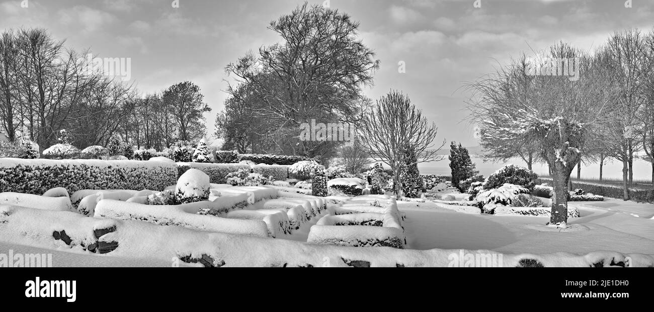 Cimetière sombre dans un paysage d'hiver monochrome. Pierres tombales enneigées contre un ciel gris nuageux. Cimetière noir et blanc dépoli vide et Banque D'Images