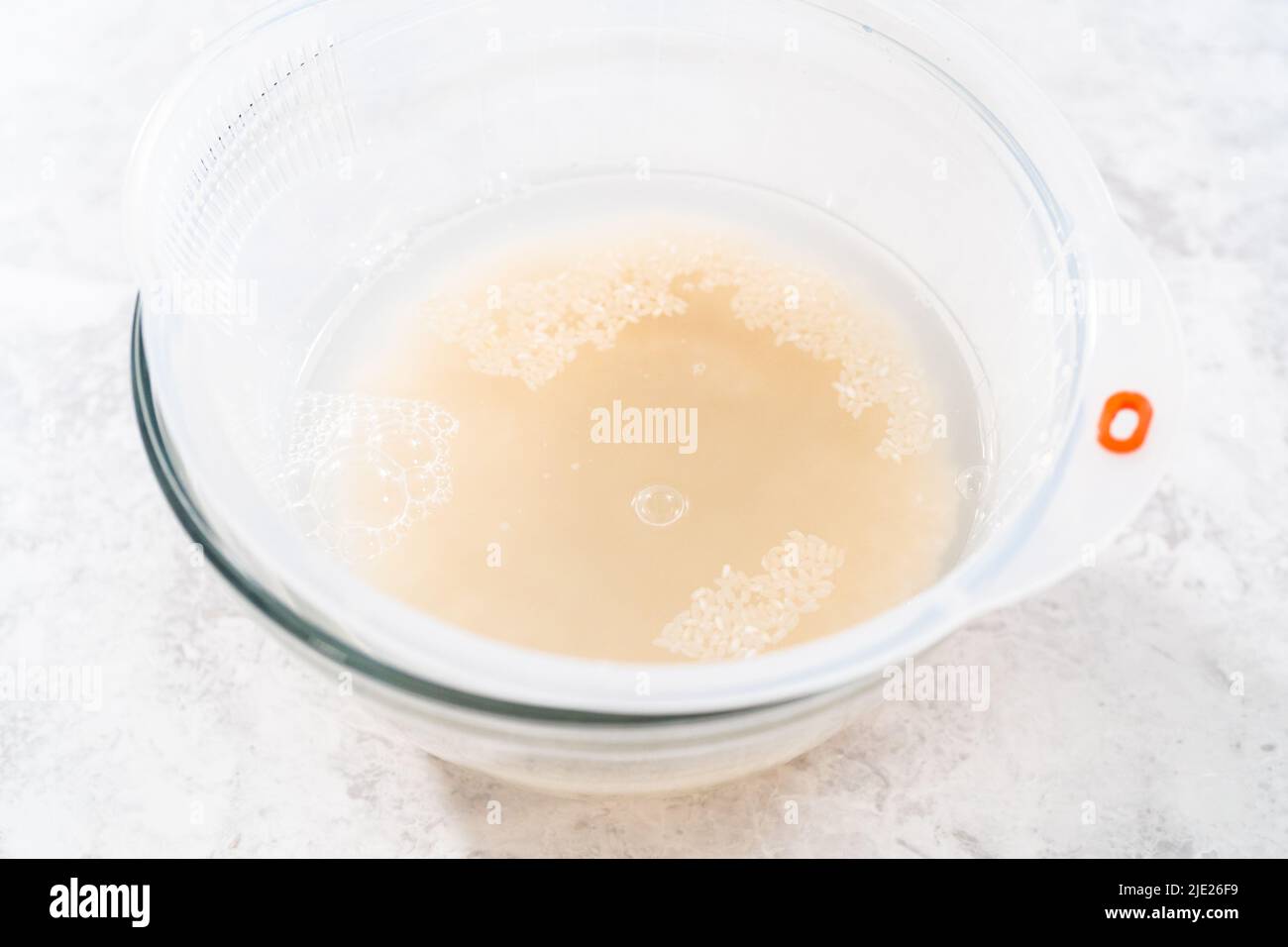 Laver le riz sec dans un lave-riz et un grand bol en verre. Banque D'Images Laver le riz sec dans un lave-riz et un grand bol en verre. Banque D'Images