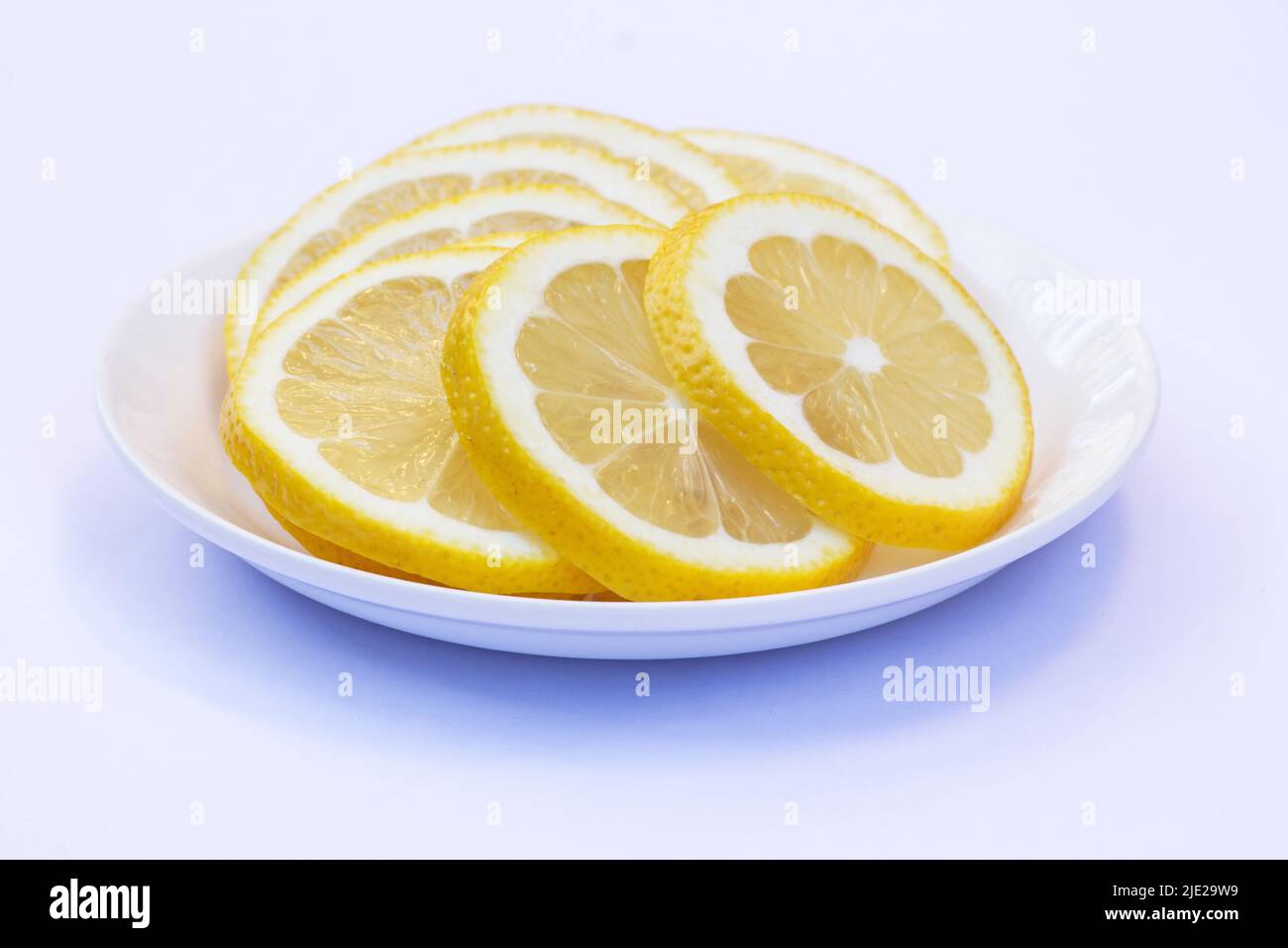 Tranches de citrons sur une plaque blanche isolée sur fond blanc Banque D'Images
