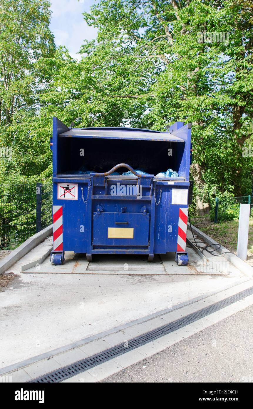 gros plan d'un compacteur à déchets bleu pour avec des réflecteurs et des affiches Banque D'Images