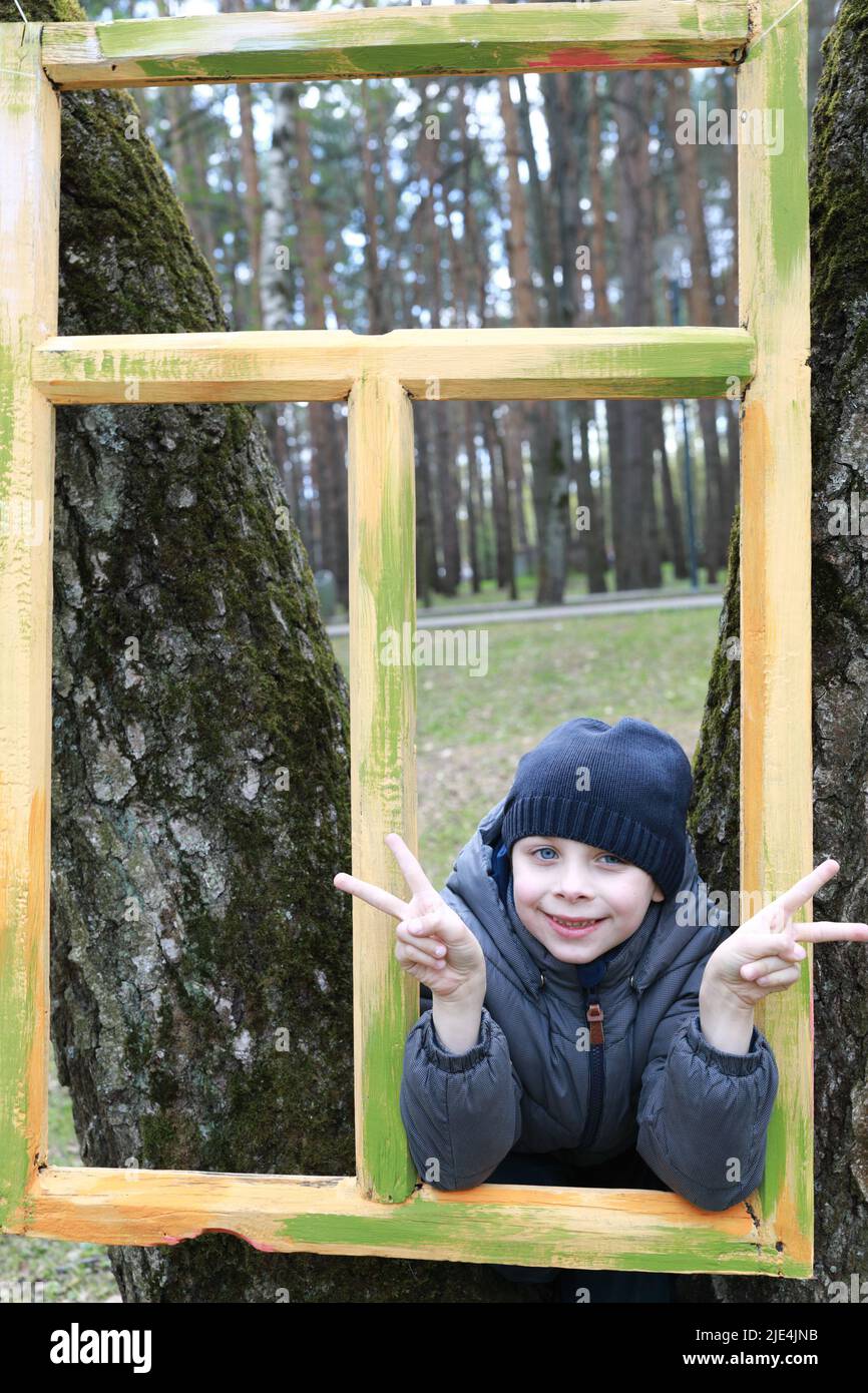 Enfant regardant à travers le cadre en bois dans le parc Banque D'Images