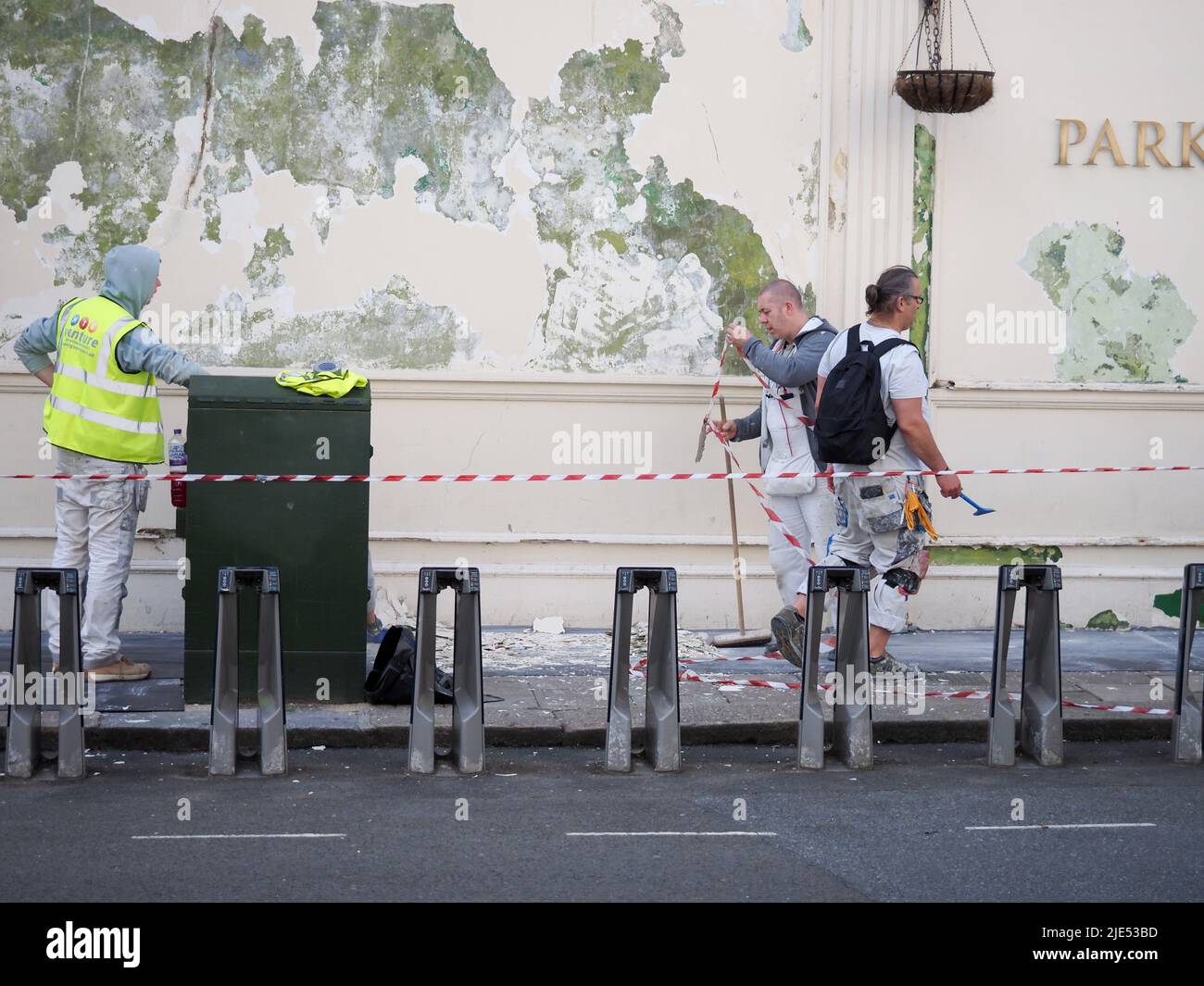 Trois hommes de travail rénovent et peignent un mur extérieur Banque D'Images