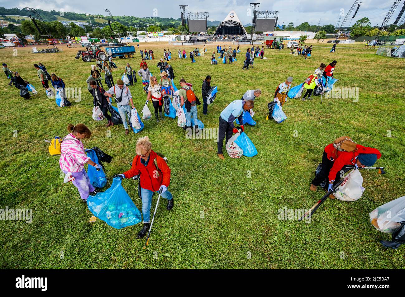 Pilton, Royaume-Uni. 25th juin 2022. Des milliers de bénévoles (beaucoup de collecte d'argent pour les organismes de bienfaisance) nettoient les déchets laissés par les festivaliers la nuit précédente (dans ce cas à l'étape Pyramid). Le travail est nécessaire en dépit de la devise du festival pour «ne laisser aucune trace» - le Glastonbury Festival 50th 2022, digne ferme. Glastonbury, Credit: Guy Bell/Alamy Live News Banque D'Images