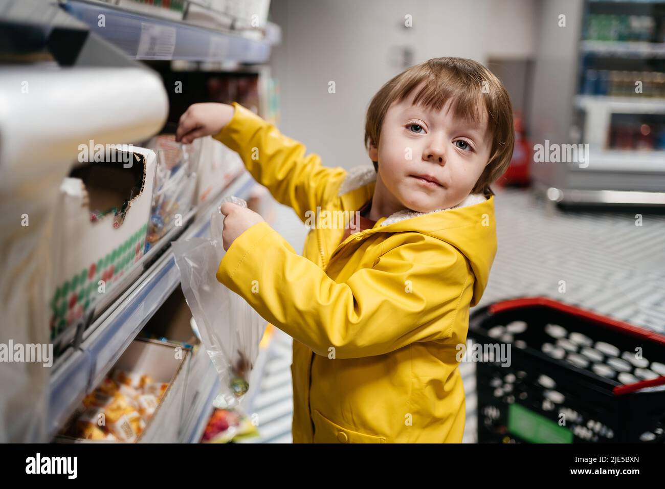 enfant sur le marché avec un chariot d'épicerie, met des bonbons dans un sac Banque D'Images