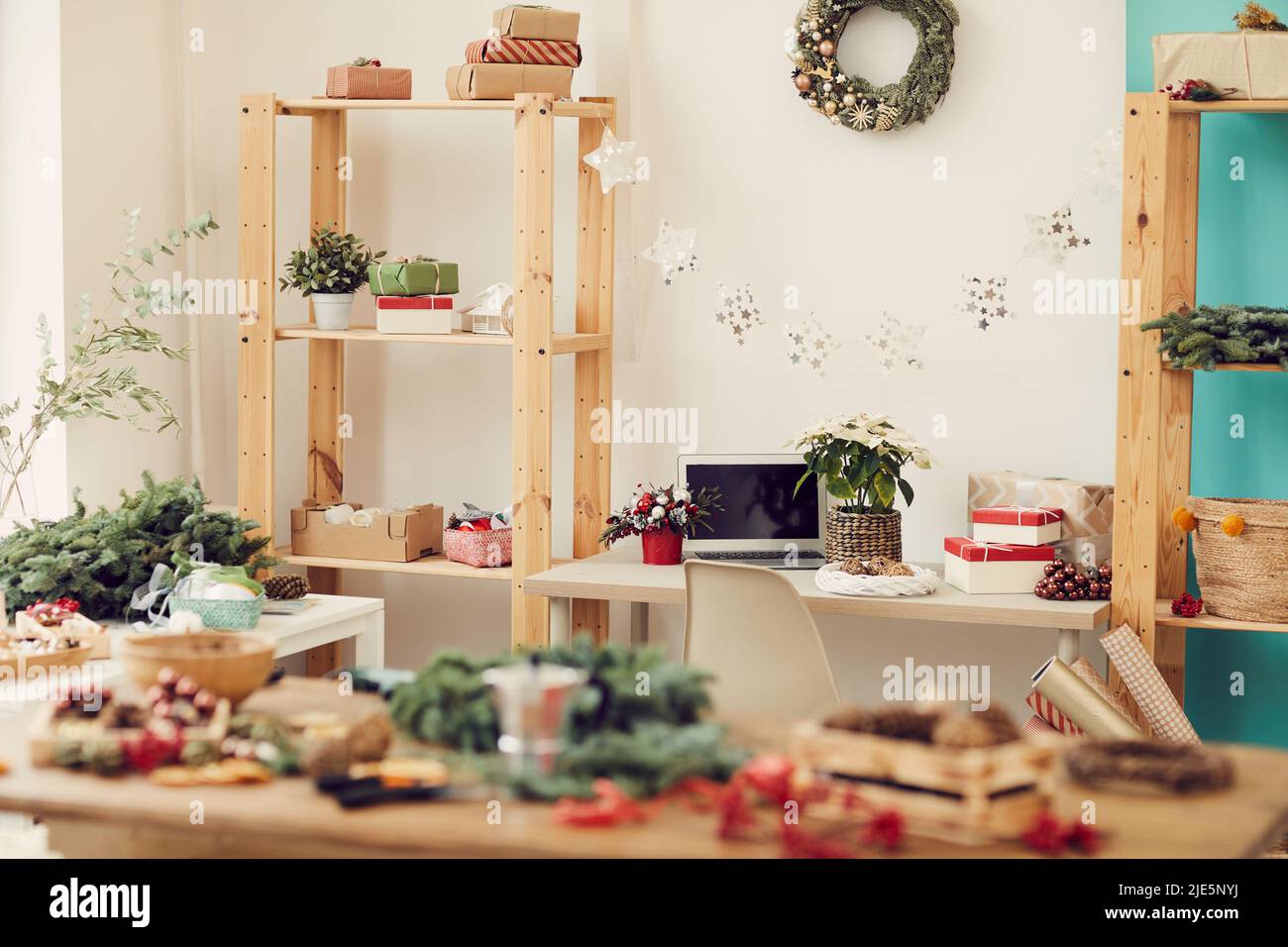 Intérieur d'un atelier moderne plein de décorations de Noël sur les espaces de travail : couronne de Noël sur le mur, guirlande d'étoiles suspendue entre les étagères avec boîte cadeau Banque D'Images