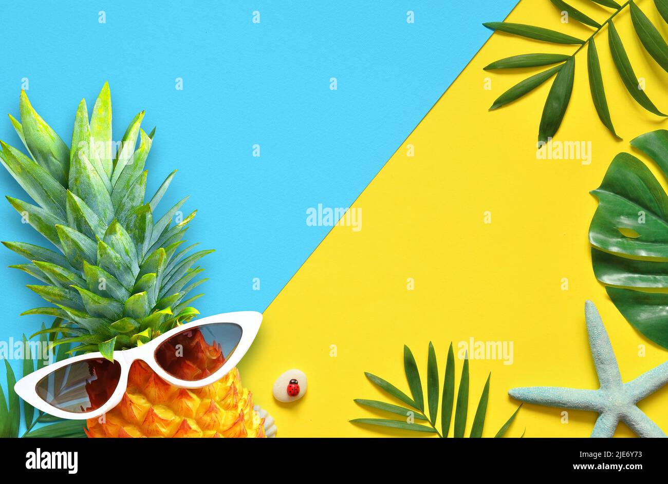 Arrière-plan d'été. Feuille de palmier, ananas en lunettes de soleil, étoiles de mer et coquillages sur fond jaune Banque D'Images