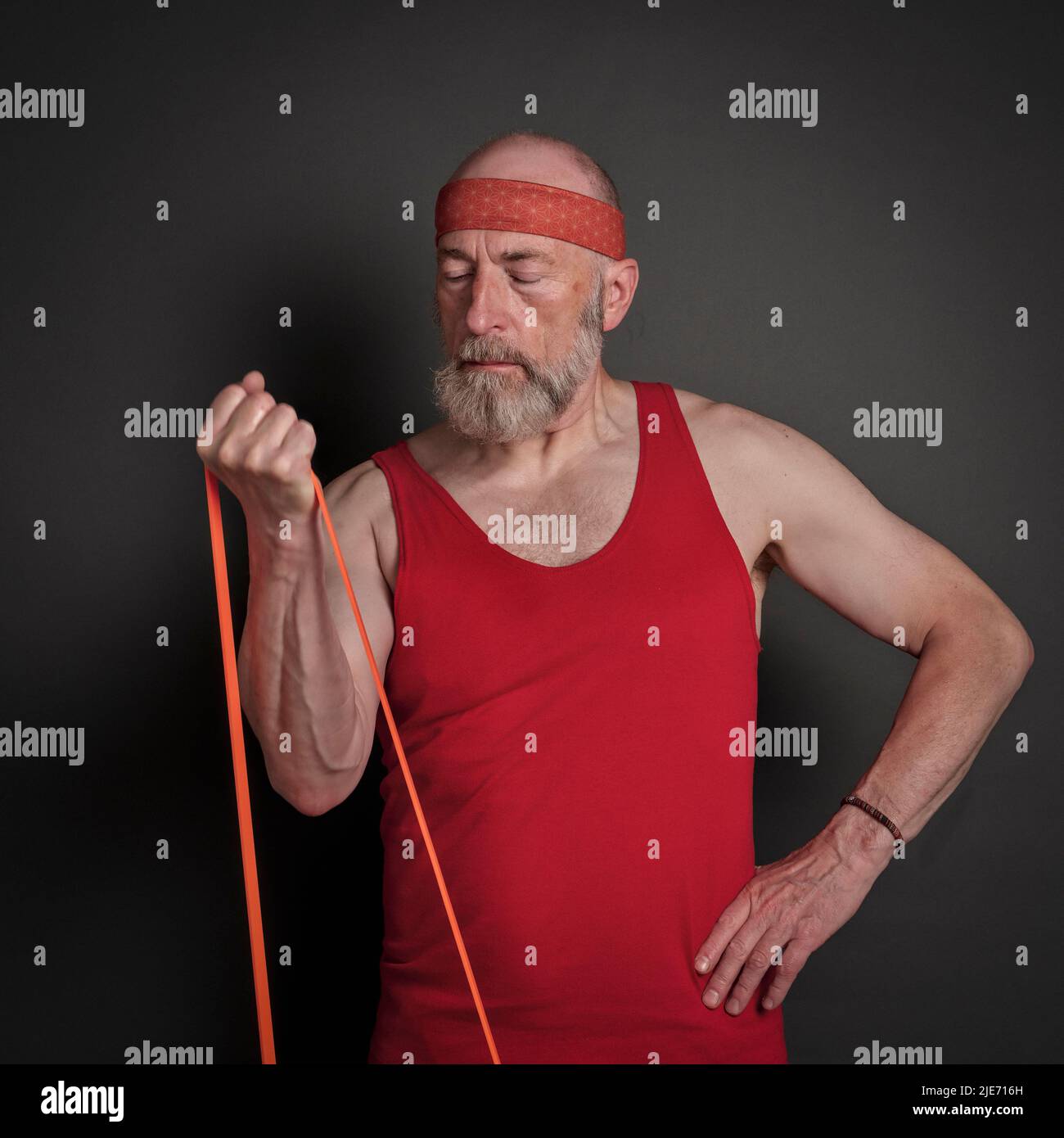 portrait de la tête et de l'épaule de l'homme âgé (fin 60s) s'exerçant avec la bande de résistance, forme physique au-dessus de 60 concept Banque D'Images