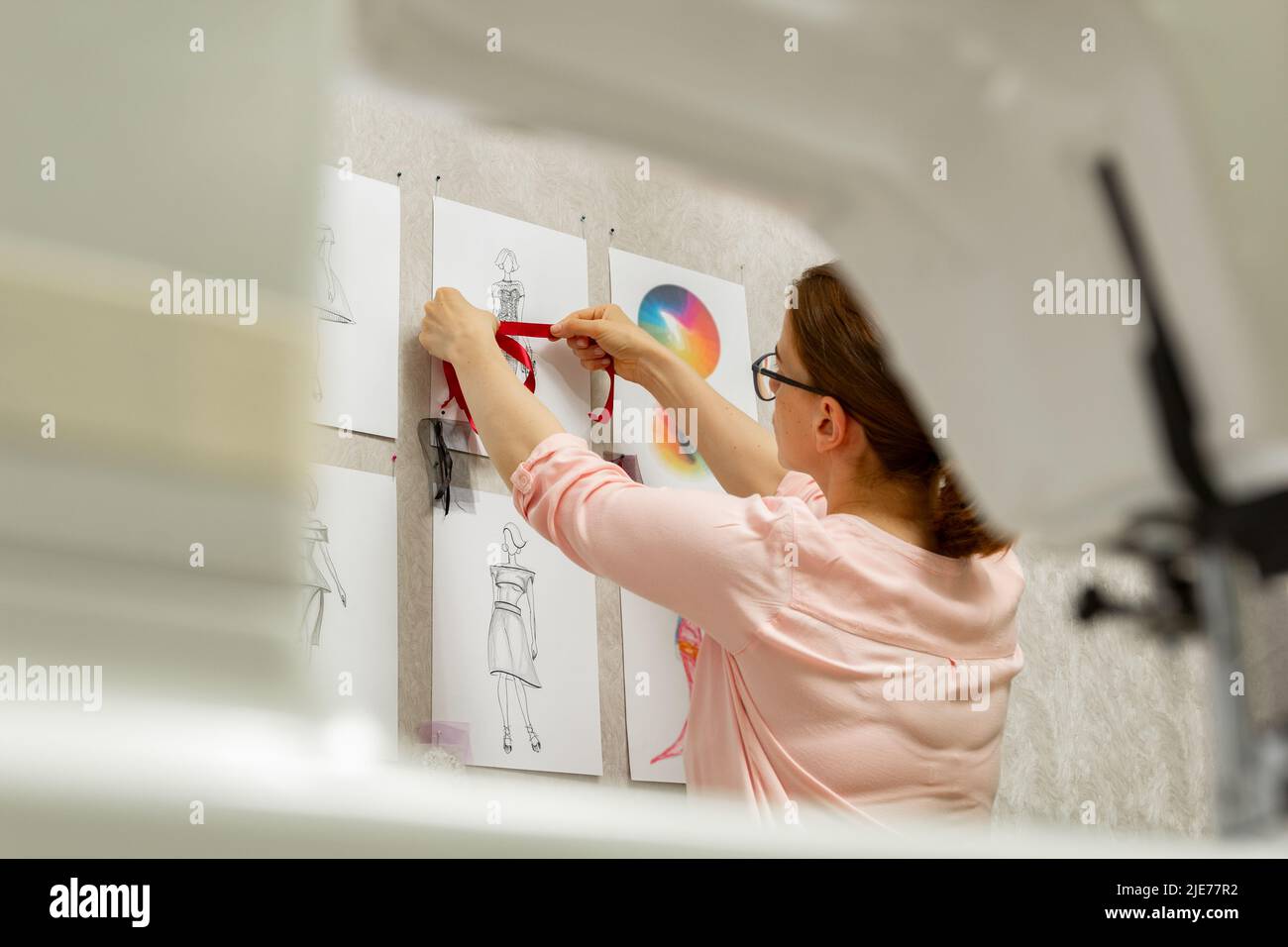 Le designer de mode développe des croquis de la conception de vêtements. L'artiste crée des robes pour femmes. Travailler sur mesure avec le tissu. Banque D'Images