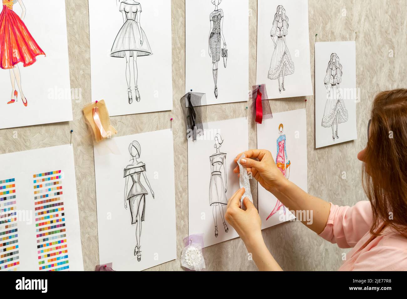 Le designer de mode développe des croquis de la conception de vêtements. L'artiste crée des robes pour femmes. Travailler sur mesure avec le tissu. Banque D'Images