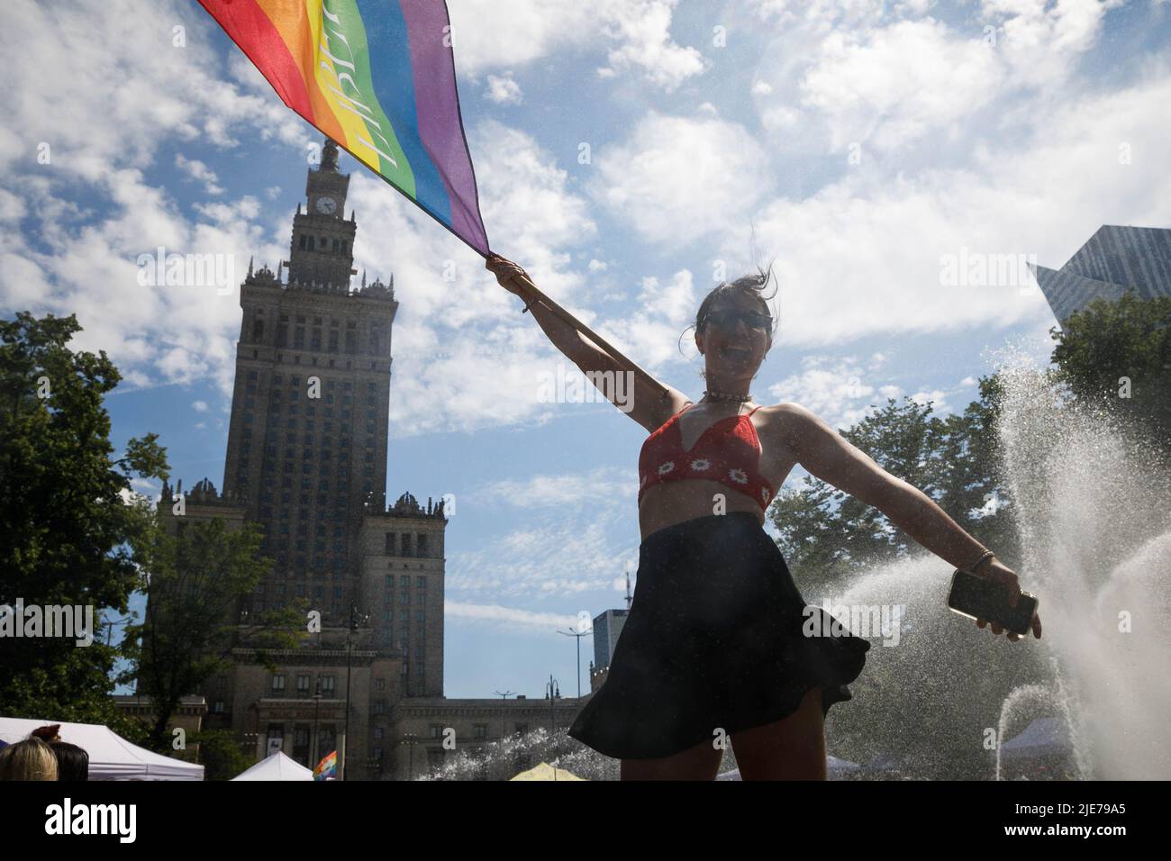 Une femme agitant le drapeau arc-en-ciel se tient près de la fontaine et avec le Palais de la Culture et de la Science en arrière-plan pendant qu'elle participe à la Parade de l'égalité de Varsovie. Le défilé a été organisé pour promouvoir l'égalité sociale et attirer l'attention sur les problèmes rencontrés par la communauté LGBT en Pologne. Cette année, le défilé de Varsovie pour l'égalité a accueilli la fierté de Kiev, la plus grande parade des droits LGBTQ d'Ukraine. Outre les slogans LGBTQ et Egalité, les participants ont montré leur soutien contre la guerre et les invasions de la Russie en Ukraine. (Photo de Volha Shukaila/SOPA Images/Sipa USA) Banque D'Images