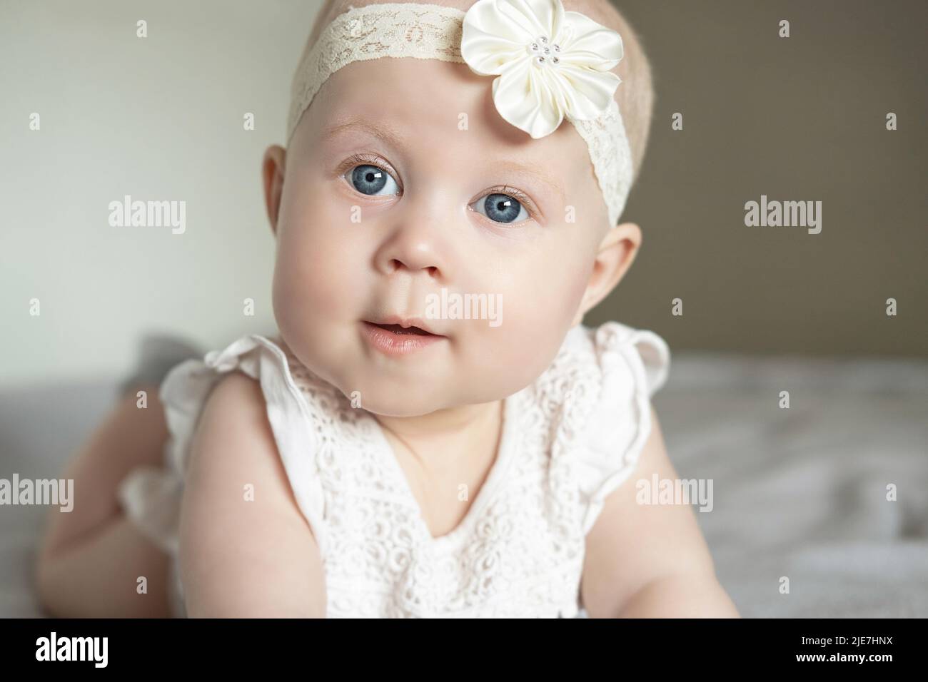 Portrait d'une belle petite fille couchée sur son ventre et regarde loin avec admiration. Bébé avec de grands yeux bleus. Concept de famille heureux Banque D'Images