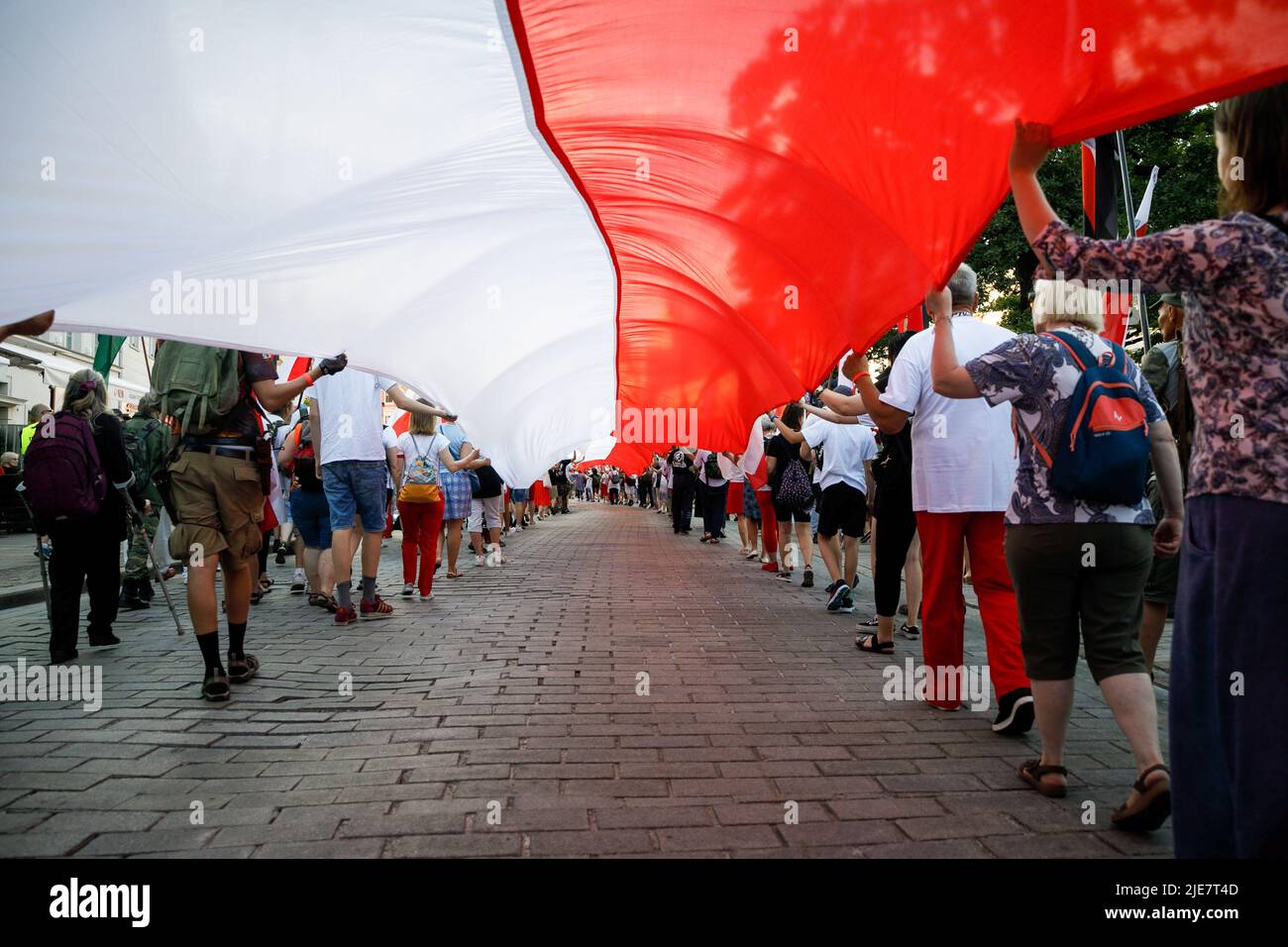 Varsovie, Pologne. 25th juin 2022. Les manifestants portent un immense drapeau rouge-blanc polonais pendant la deuxième marche de Dmowski jusqu'au château. La deuxième marche de Dmowski au château a été organisée par les nationalistes polonais. Roman Dmowski était un politicien polonais, co-fondateur et principal idéologue de la démocratie nationale polonaise. Au cours du mois de mars, les participants avec le drapeau national polonais marchent dans les rues de Varsovie avec le buste de Dmowski. Crédit : SOPA Images Limited/Alamy Live News Banque D'Images