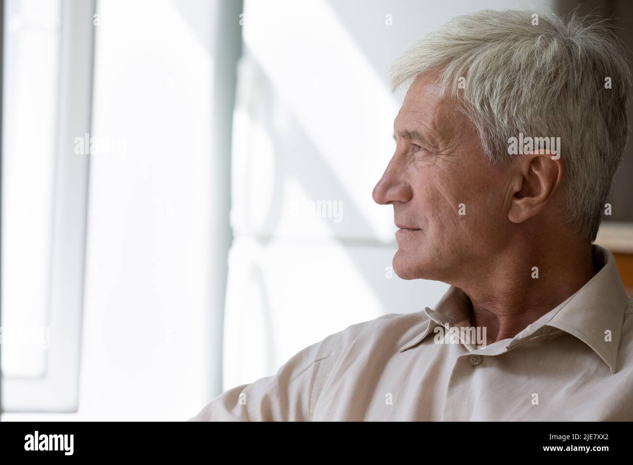 Vue de profil latérale pensive homme plus âgé s'assoir en regardant la fenêtre Banque D'Images