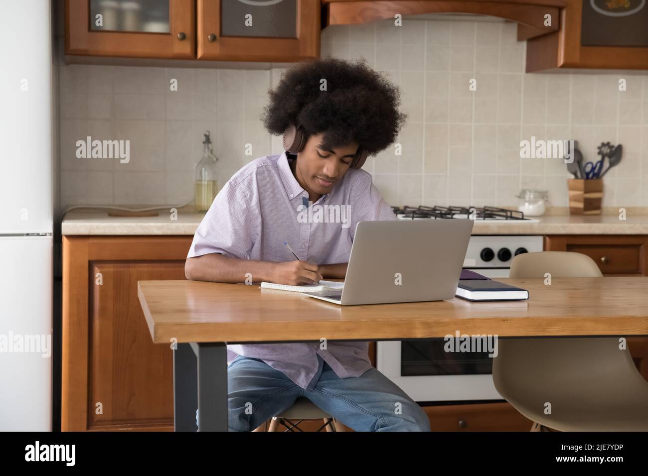 Un étudiant africain dans le casque d'écoute faire des devoirs d'université utiliser un ordinateur portable Banque D'Images