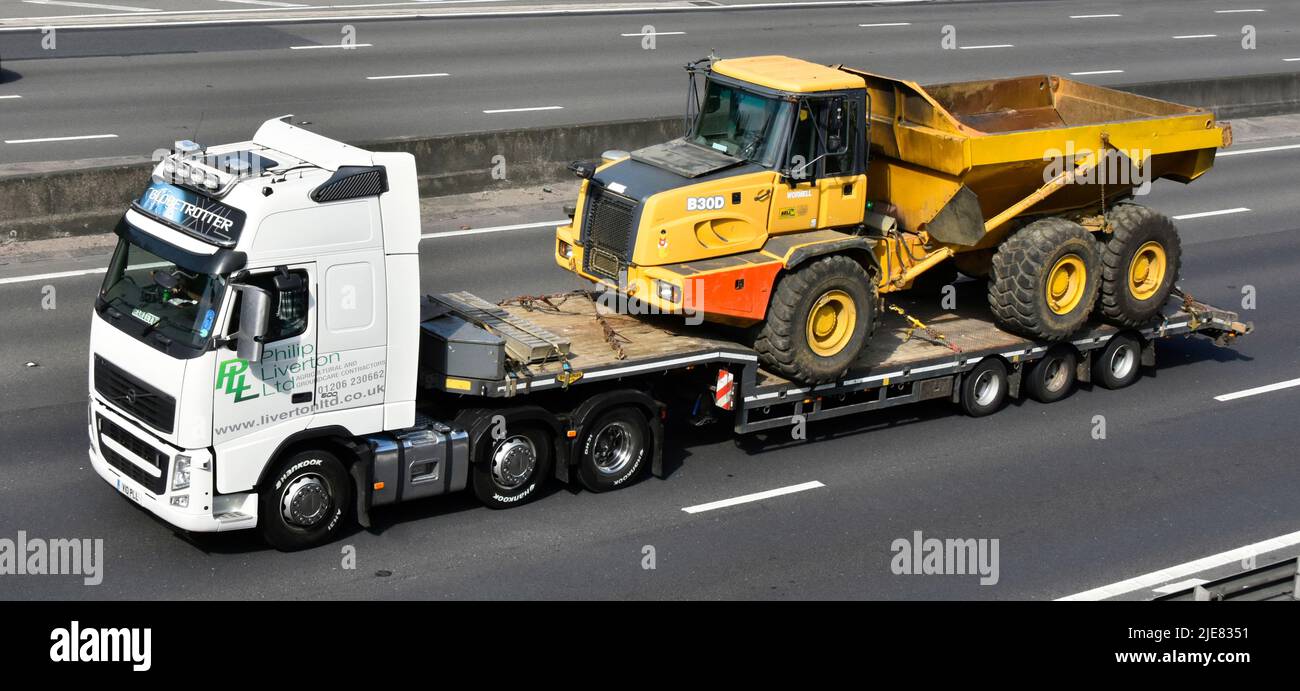 Entreprise de transport conduite de camions hgv et remorque à chargeur bas transportant un camion benne basculante articulée Bell B300 jaune sur l'autoroute britannique Banque D'Images