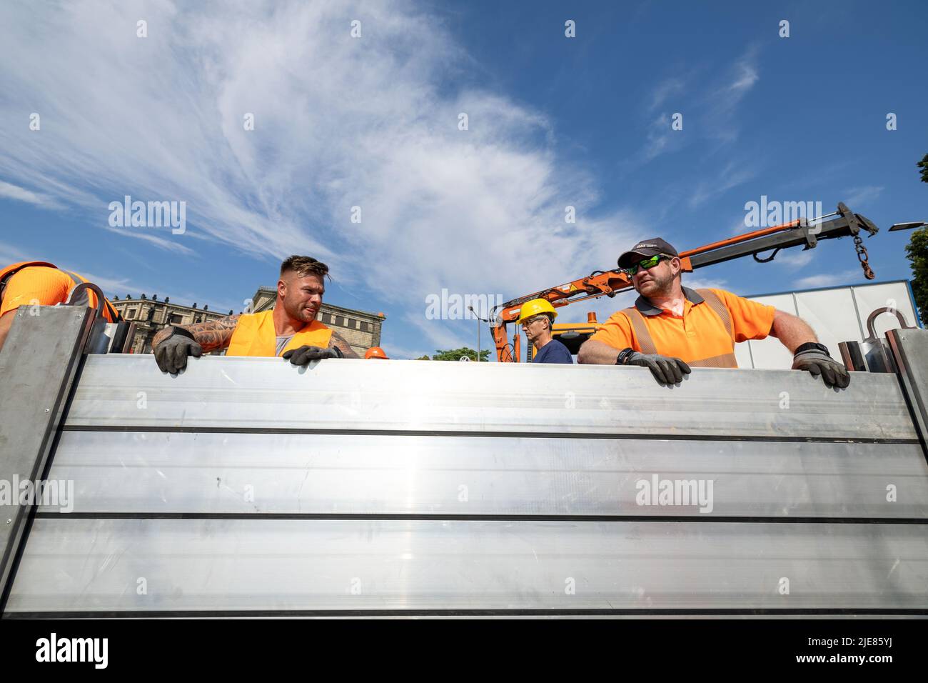 Dresde, Allemagne. 26th juin 2022. Deux employés du Regiebetrieb Zentrale Technische Dienstleistungen (RB ZTDL) de la ville installent un élément de protection contre les inondations dans l'appareil. Lors de l'installation d'essai du système de protection mobile contre les inondations dans le centre-ville de Dresde, des travaux d'entretien sont effectués sur le système, les éléments sont nettoyés et leur fonctionnalité testée. Credit: Daniel Schäfer/dpa/Alay Live News Banque D'Images