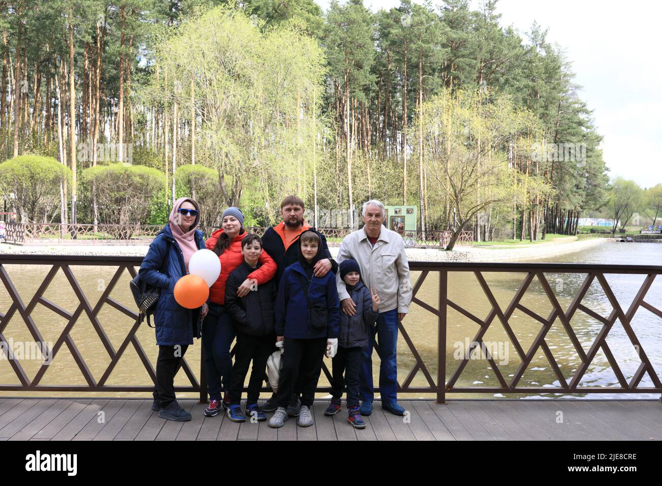 Famille posant sur la rive de l'étang dans le parc Banque D'Images