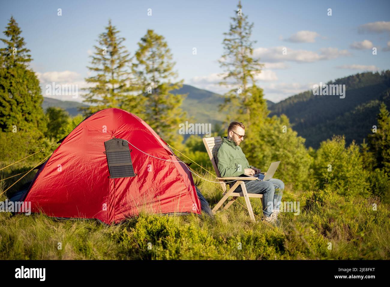 L'homme travaille sur ordinateur portable au camping dans les montagnes Banque D'Images