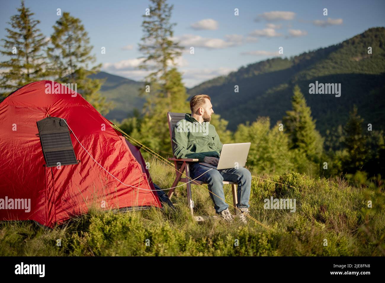 L'homme travaille sur ordinateur portable au camping dans les montagnes Banque D'Images