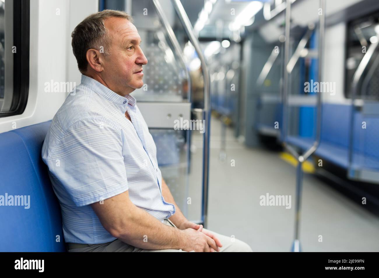 Homme d'âge moyen assis dans une voiture de métro Banque D'Images