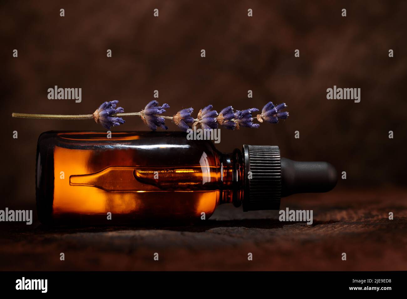 Une bouteille d'huile cosmétique de lavande repose sur un fond en bois. Maquette d'un produit cosmétique. Image conceptuelle. Banque D'Images