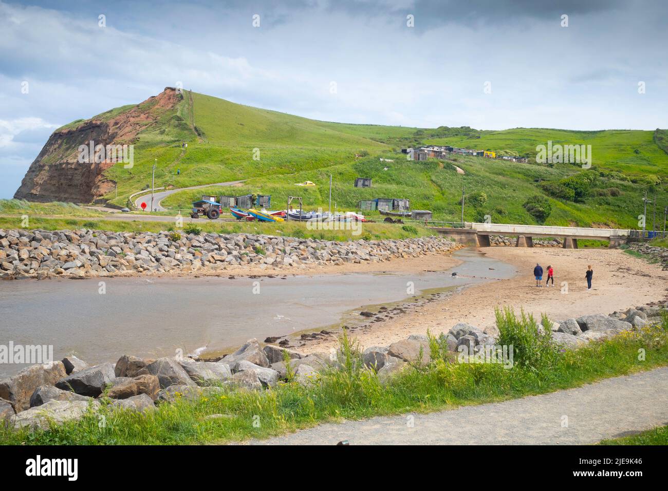 Trois personnes avec un chien marchant sur la plage à marée basse dans le port de Skinningrove North Yorkshire Angleterre Banque D'Images