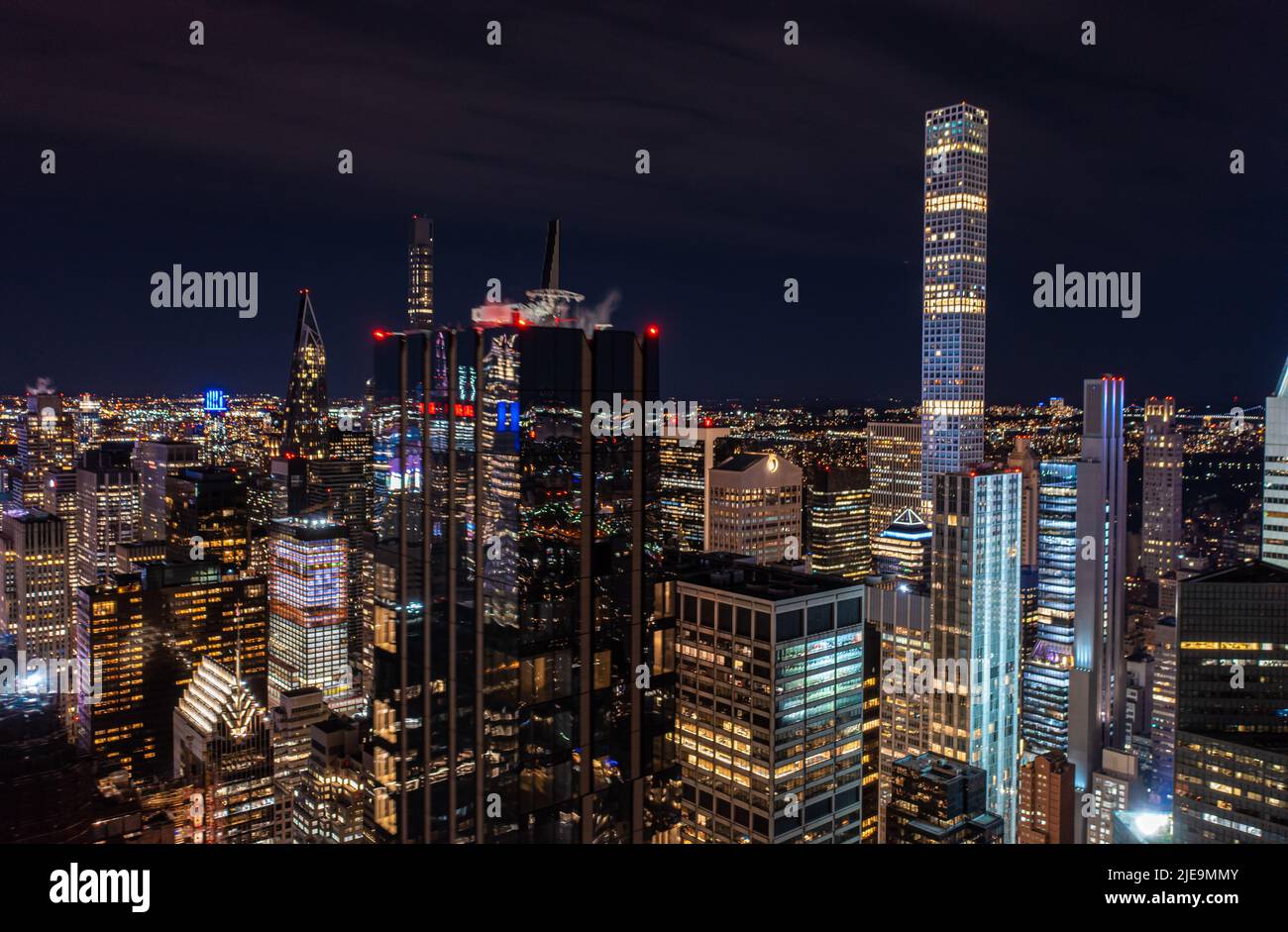 Scène nocturne de la ville avec des bâtiments modernes de haute élévation dans la métropole. Façade en verre sombre brillant reflétant les lumières environnantes. Manhattan, New York, États-Unis Banque D'Images