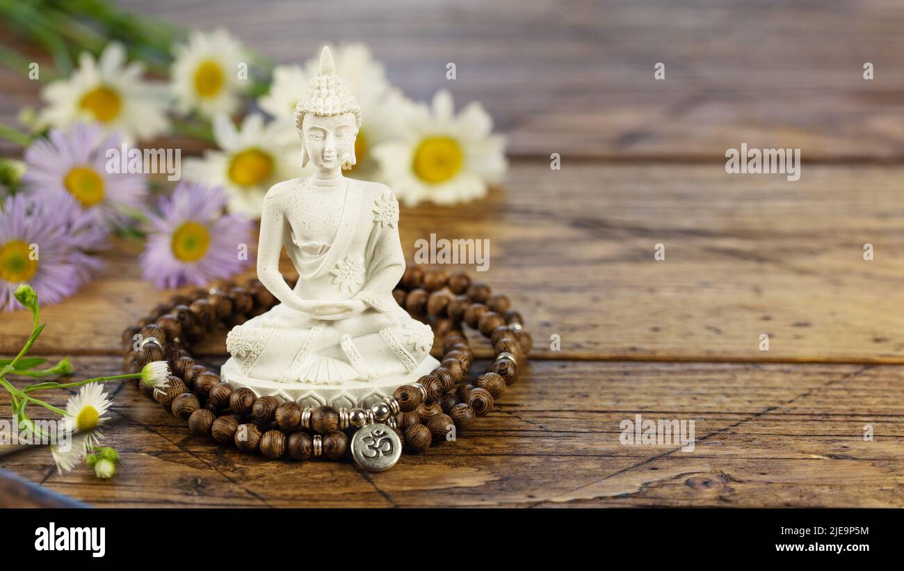 Vesak, Fête du Bouddha. Statue de Bouddha, perles de prière et fleurs sur fond de bois avec espace de copie. Procédure et méditation rituelles spa asiatiques. Energie Banque D'Images