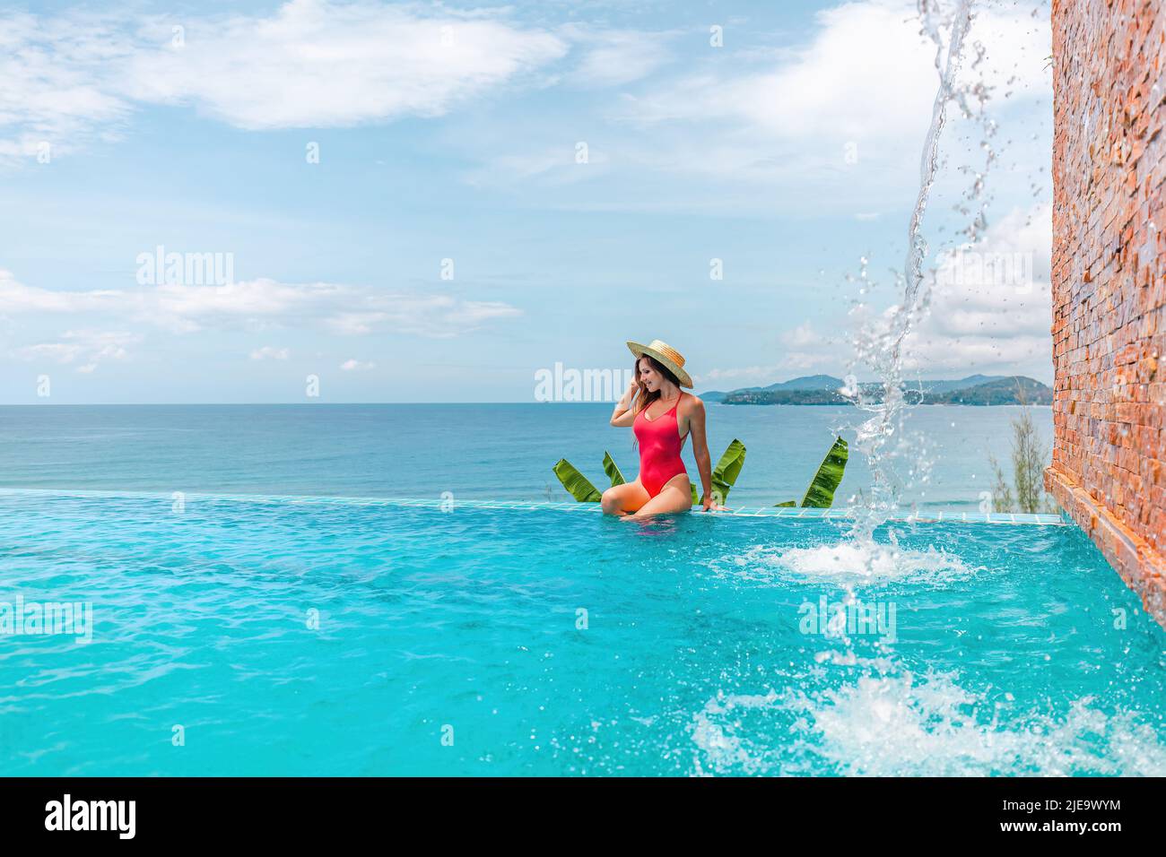 Vacances d'été avec vue sur la mer. Jeune femme en maillot de bain assis au bord de la piscine Banque D'Images