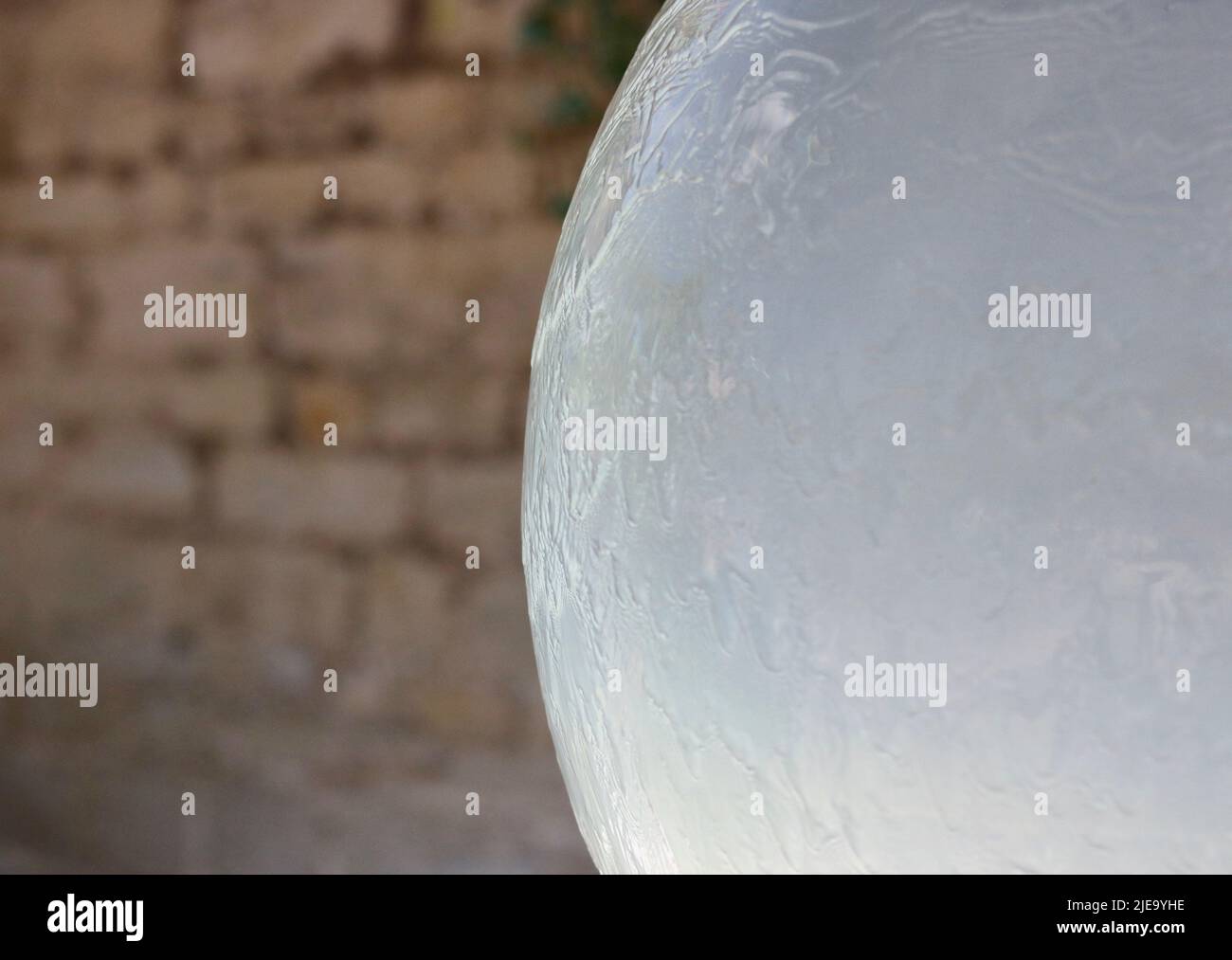 Côté d'une grande boule sphérique de glace ou d'une fontaine d'eau avec fond de mur de brique Banque D'Images