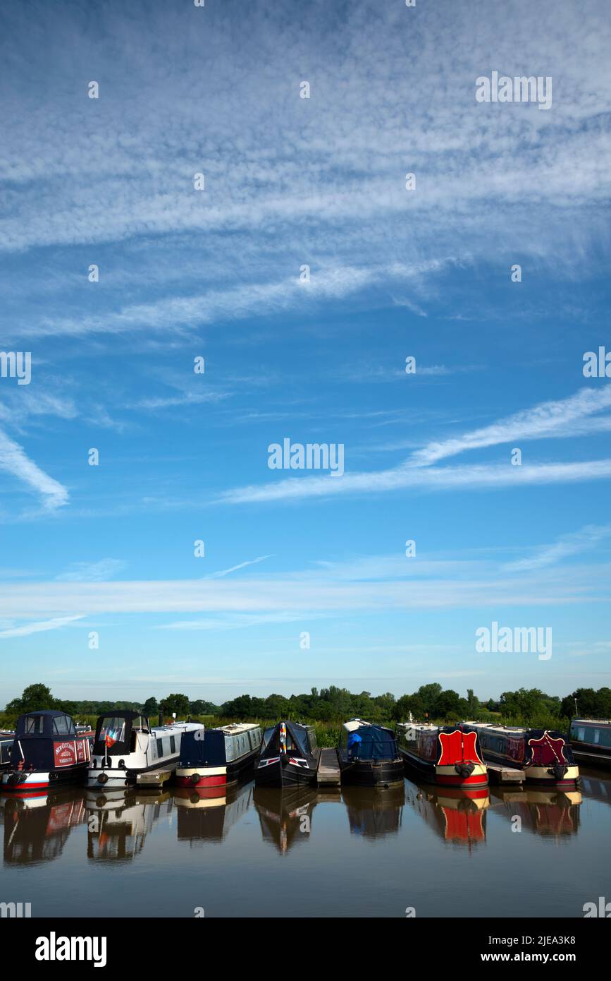 Des bateaux étroits amarrés dans un port de plaisance de Cheshire, dans un ciel bleu, avec des pistes de vapeur provenant des avions qui passent Banque D'Images