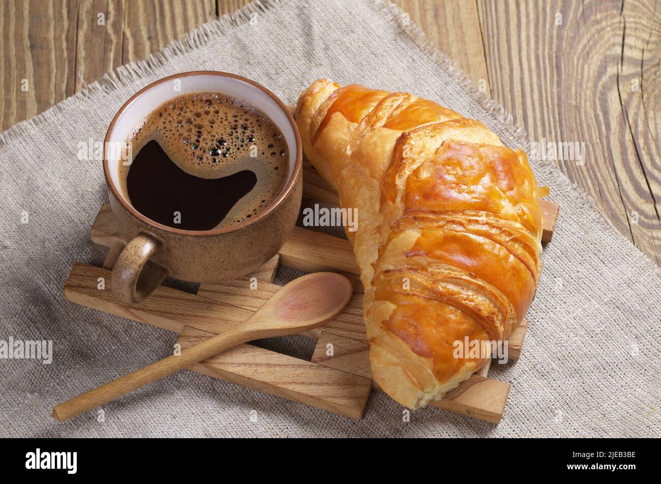 Une tasse de café et un croissant sur une table avec un linge de lin. Thème petit déjeuner Banque D'Images