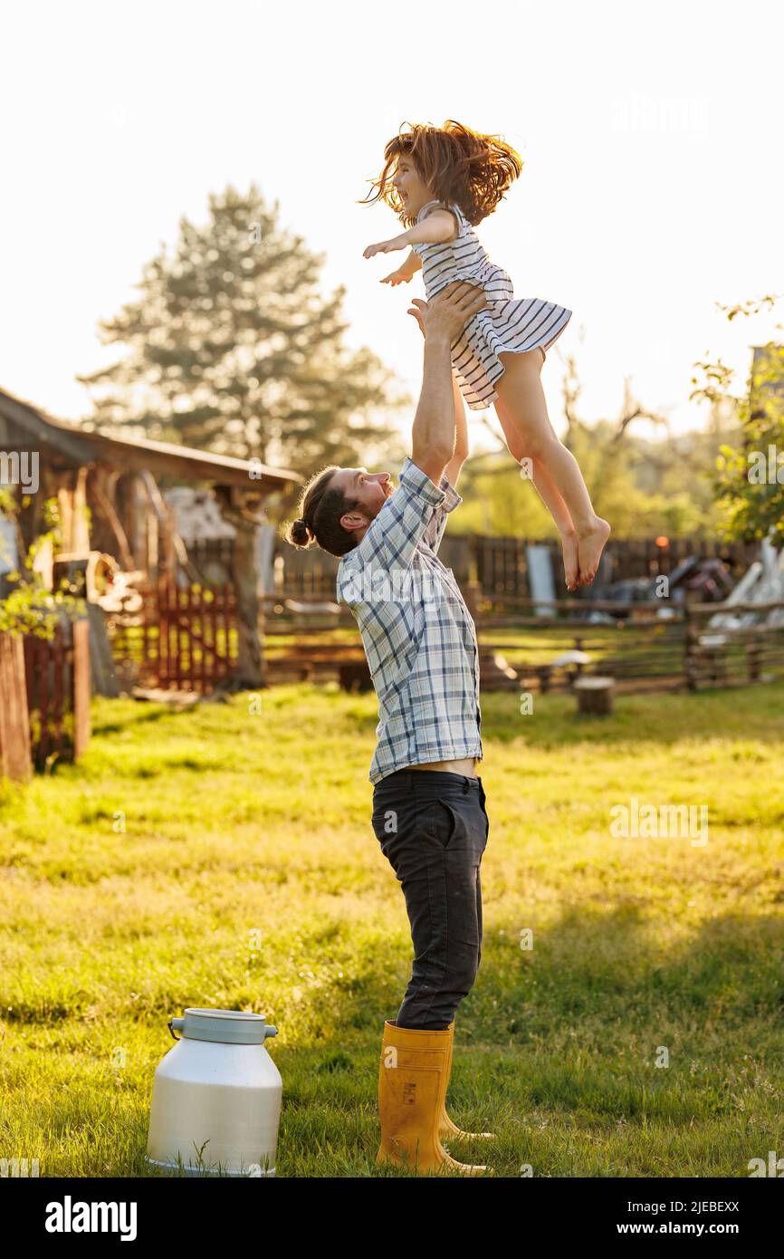 Joyeux petit enfant s'amuser avec papa dans le jardin domestique par beau temps. Père jetant son enfant dans l'air. Passer du temps ensemble le week-end à Banque D'Images