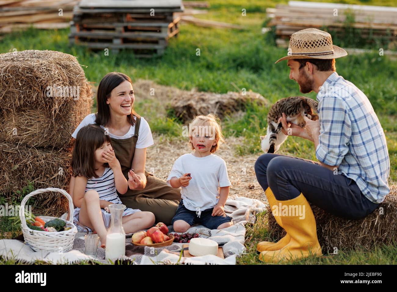 Bonne jeune famille déjeuner dans le jardin d'été. Mère, père et deux enfants aiment passer du temps ensemble le week-end à la campagne. Pique-nique Banque D'Images