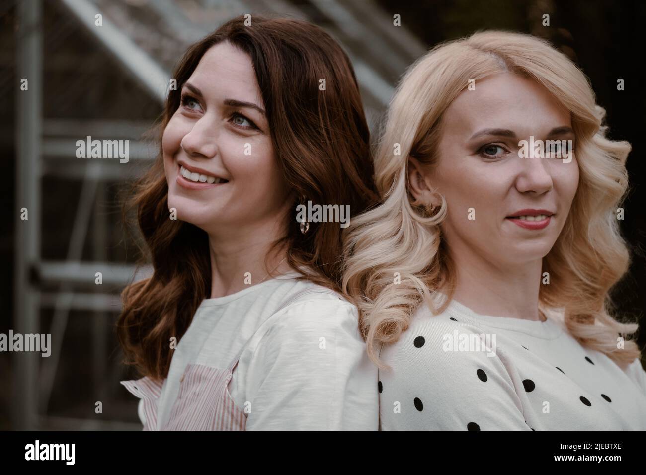 Deux sœurs matures dans le jardin le soir. Portrait d'une femme à ses 40s et 30s ans, parents, liens avec la nature sur la serre et les arbres Banque D'Images