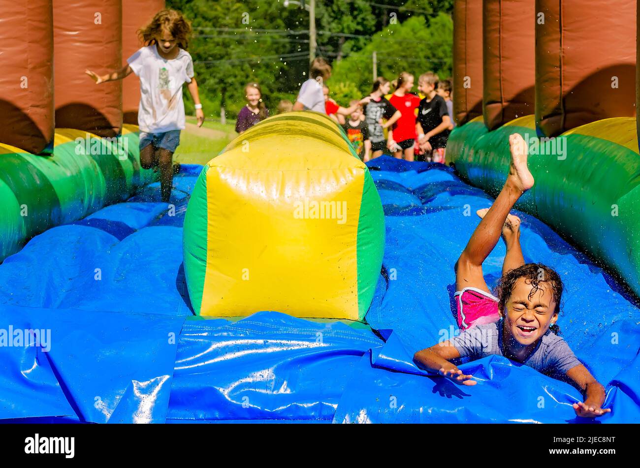 Les enfants jouent sur un toboggan aquatique gonflable, 27 juillet 2012, à Columbus, Mississippi. Banque D'Images