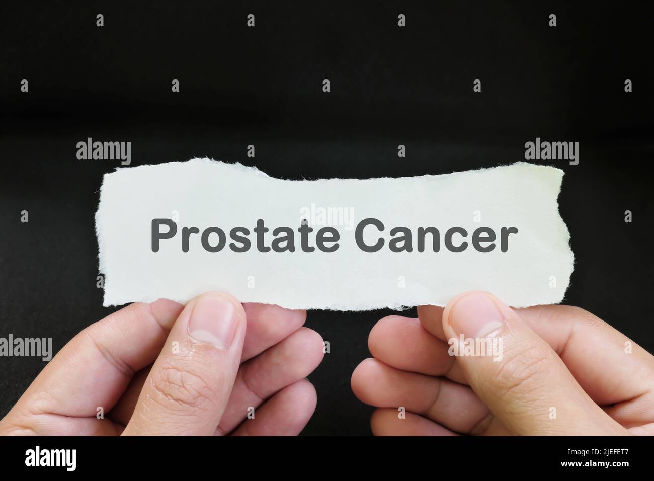 Concept de diagnostic du cancer de la prostate. Papier tenant à la main avec texte écrit sur fond noir foncé. Banque D'Images