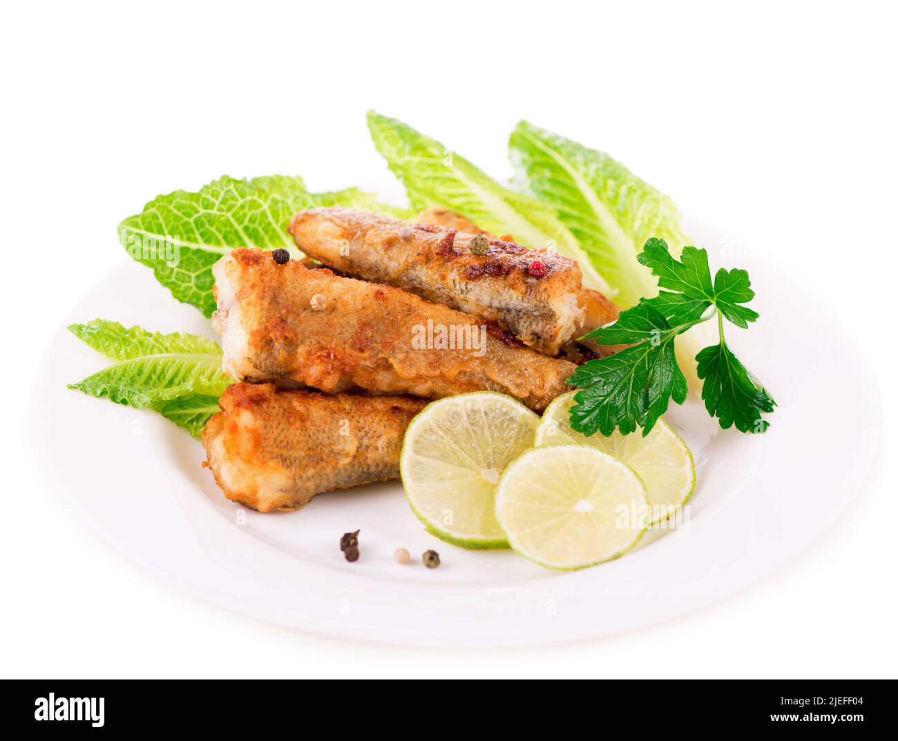 appétissant filet de poisson frit avec légumes et herbes sur une assiette blanche Banque D'Images