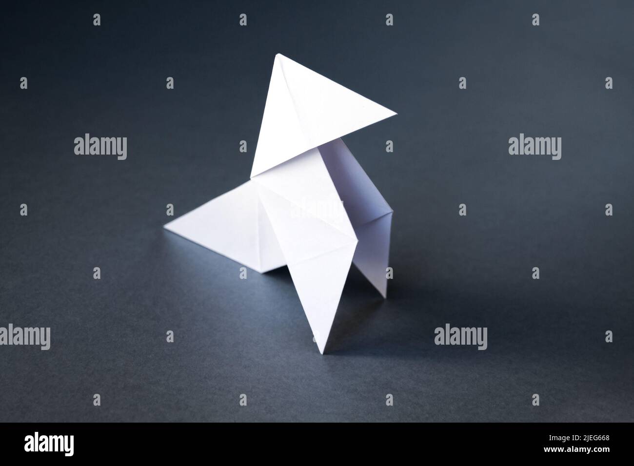 Poule de papier blanc origami isolé sur un fond gris vierge. Cocotte en papier Banque D'Images
