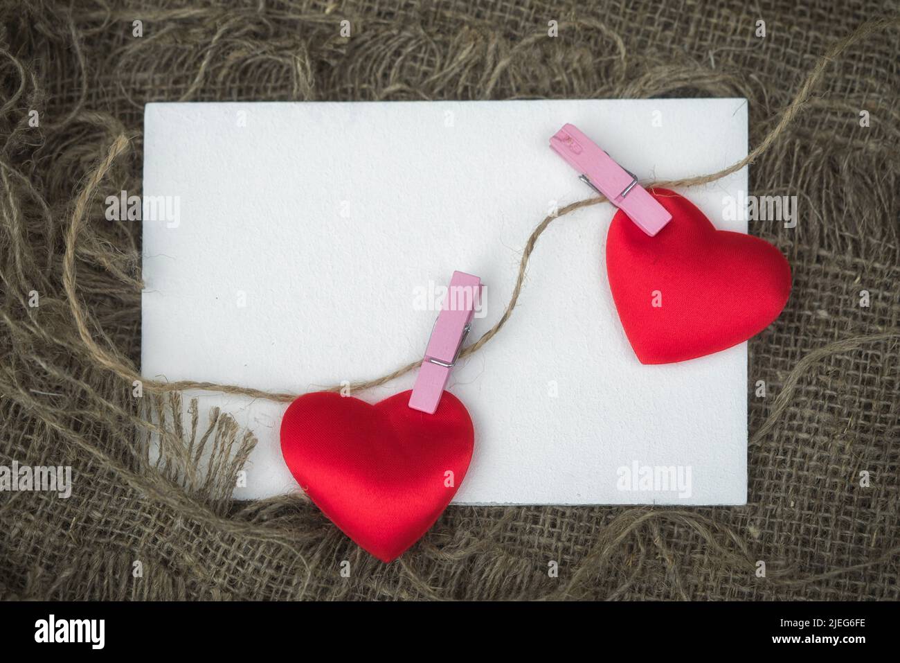 Carte de voeux avec feuille de papier vide et deux coeurs attachés avec des épingles à linge à une corde avec espace de copie Banque D'Images