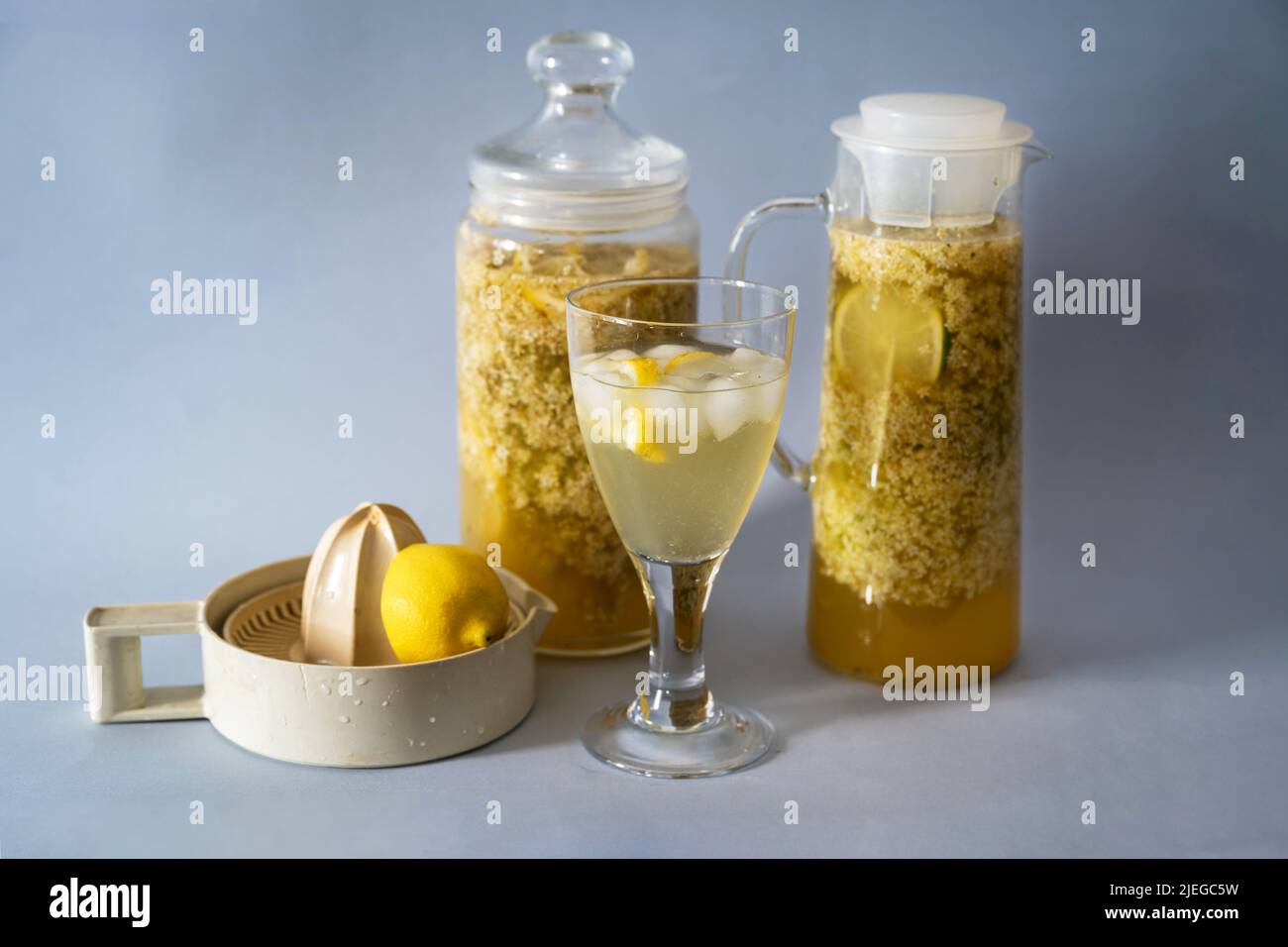 Préparation de la citrup de sureau, lixiviation de la fleur de sureau en deux verres, boisson et presse-agrumes sur fond gris. Banque D'Images