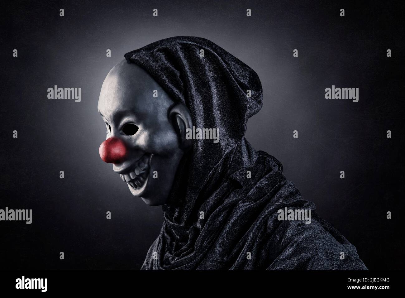 Clown effrayant montrant ses dents sur fond sombre et brumeux Banque D'Images