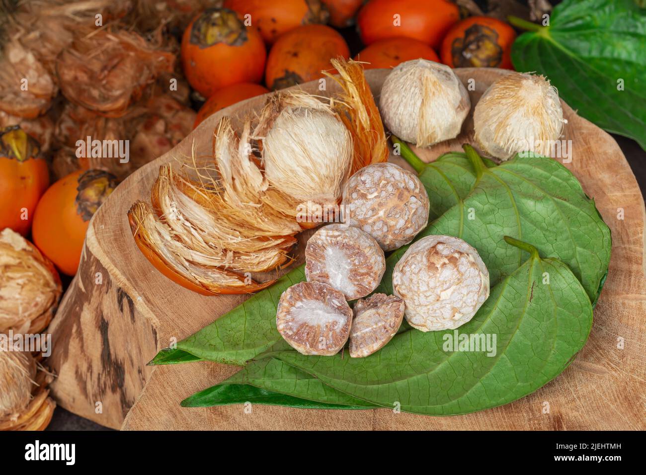 Noix de bétel mûre ou noix d'arec avec feuille de bétel isolée sur fond en bois. Banque D'Images