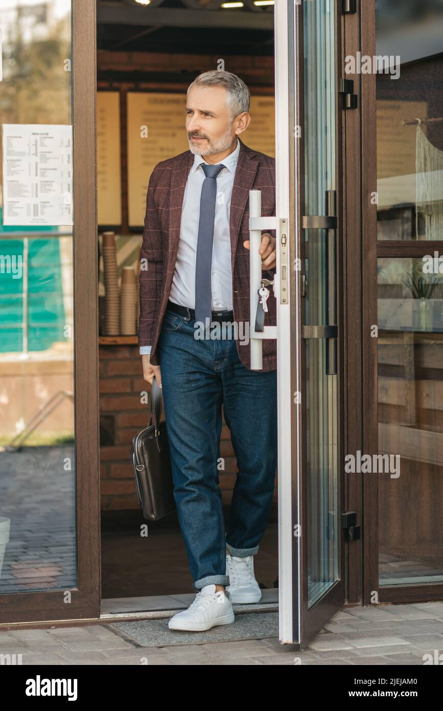 Homme avec un sac touchant la porte en quittant le bâtiment Banque D'Images