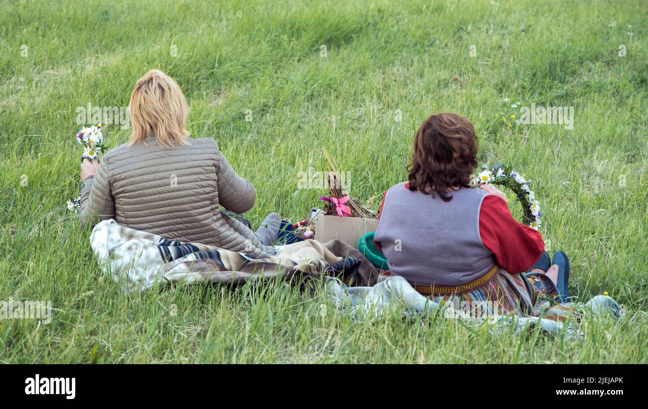LETTONIE, REKU KALNS - 21 JUIN 2022: Les femmes font une couronne de fleurs dans un pré de fleurs. Célébration des vacances midété LIGO en Lettonie Banque D'Images