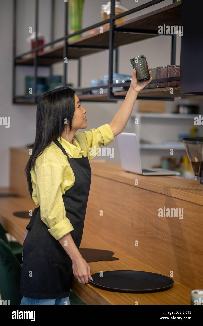 Une femme se trouvant sur le côté de l'appareil photo place le verre sur la tablette supérieure Banque D'Images