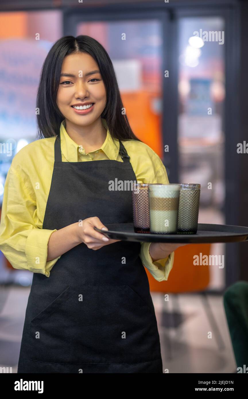 Femme tenant un plateau de boissons regardant l'appareil photo Banque D'Images