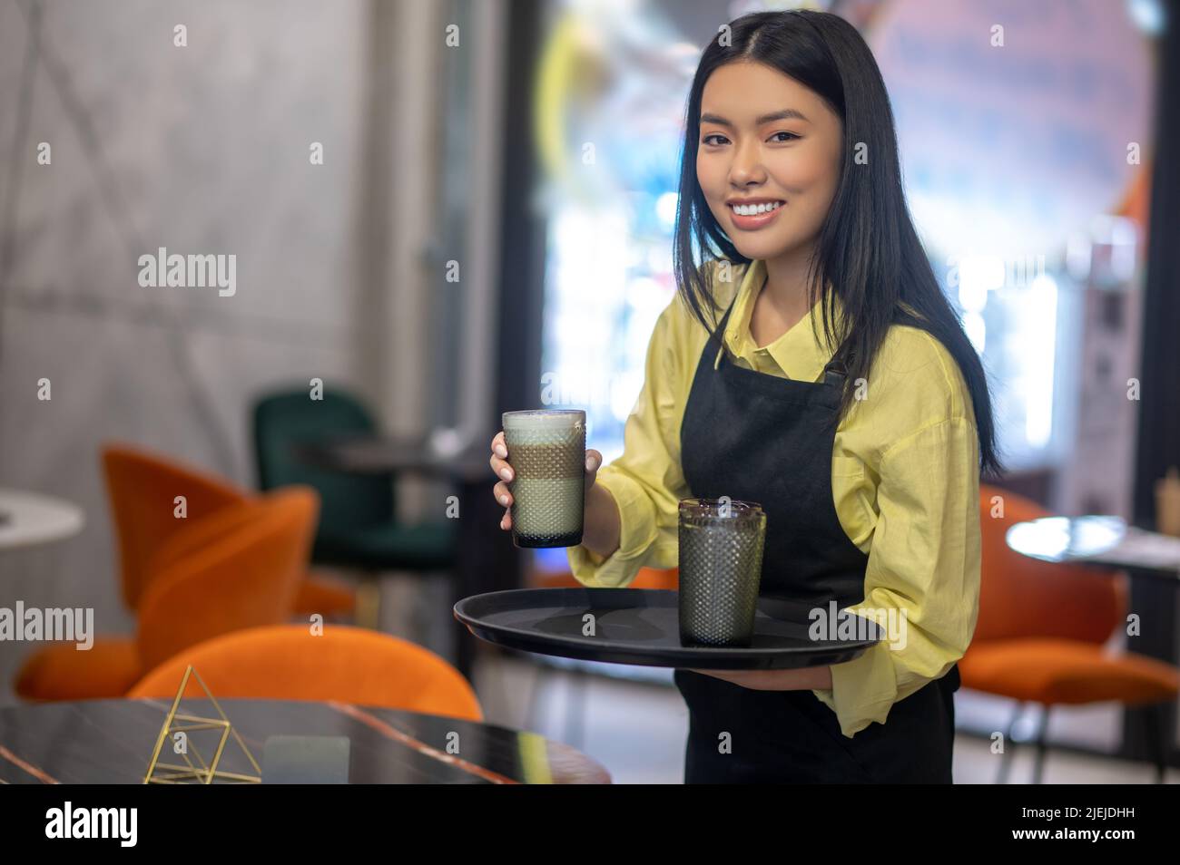 Femme avec plateau tenant le verre regardant l'appareil photo Banque D'Images